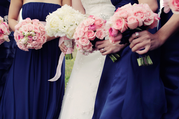 close up of bride and bridesmaids wearing dark blue dresses holding pink roses -photo by San Francisco based wedding photographer